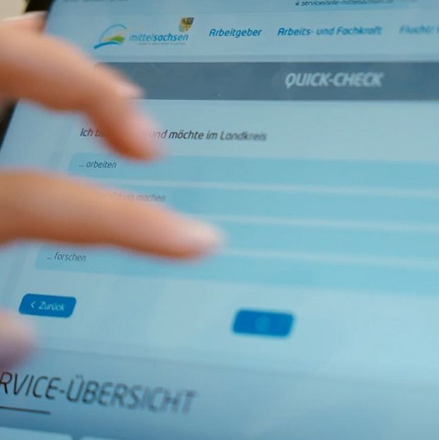 Das Bild zeigt einen Touchscreen und eine Hand, die diesen bedient. Zu lesen ist Quick Check auf der Website des SAMM.