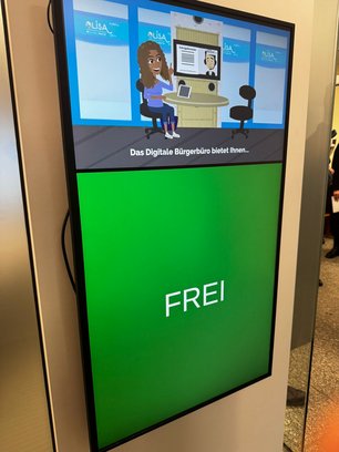 An einer Wand hängt ein Bildschirm, der die Information "frei" zeigt.
