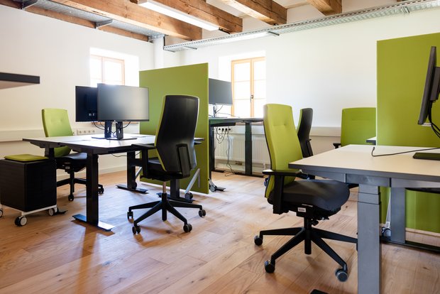 Man sieht verschiedene Arbeitsplätze mit Tisch, Stuhl und Monitor