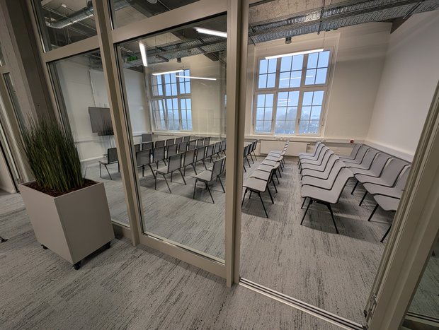 Das Bild zeigt einen modernen Veranstaltungsraum, der sich im Gebäude des Buntspeichers befindet. Der Raum verfügt über sehr große Fenster mit Blick in die umliegende Landschaft.